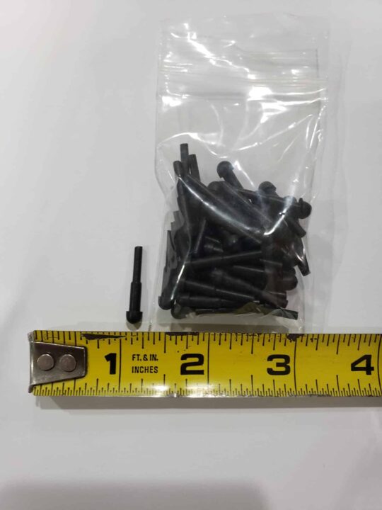 A small black metal pin, about 1.5 inches long as shown by a yellow tape measure, lies next to a bag of similar pins likely intended for use with Bulk Rubber Bumpers.